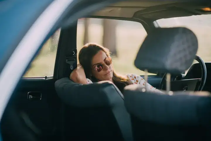 Woman with sunglasses posing on a driver seat